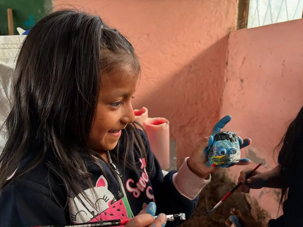Niña pintando una piedra en un taller de la fundación